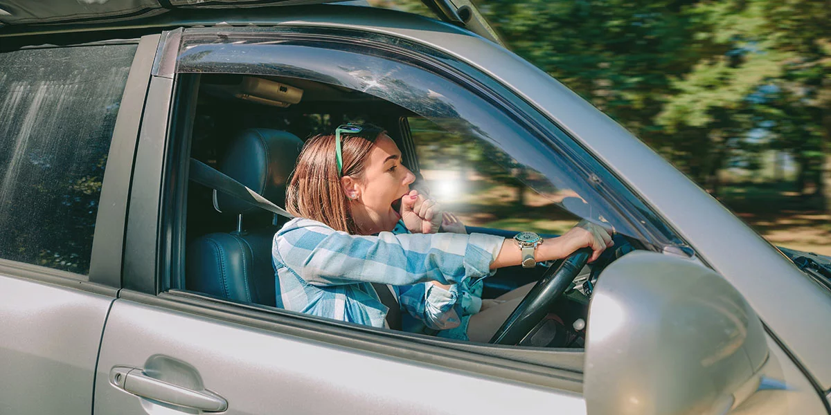 Tired yawning lady behind the wheel