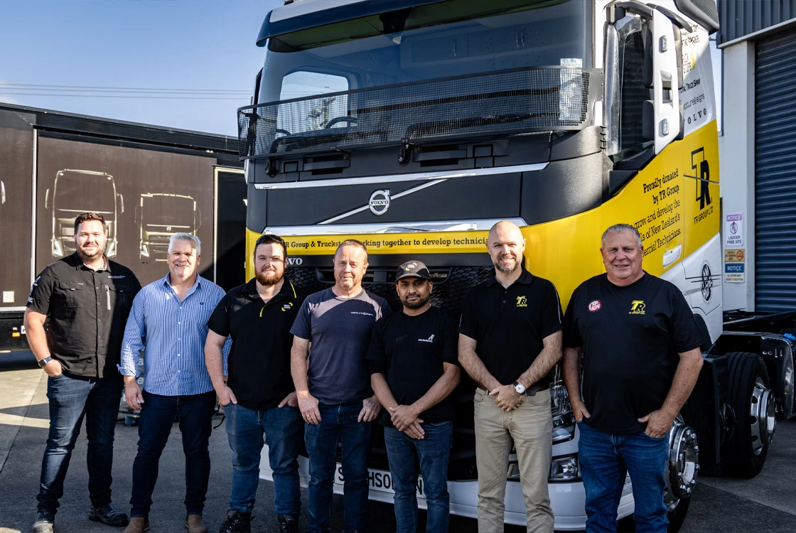 Group photo of TR Group and Truckstops team standing in front of a restored Volvo truck, showcasing their collaboration to develop training resources for future heavy vehicle technicians.